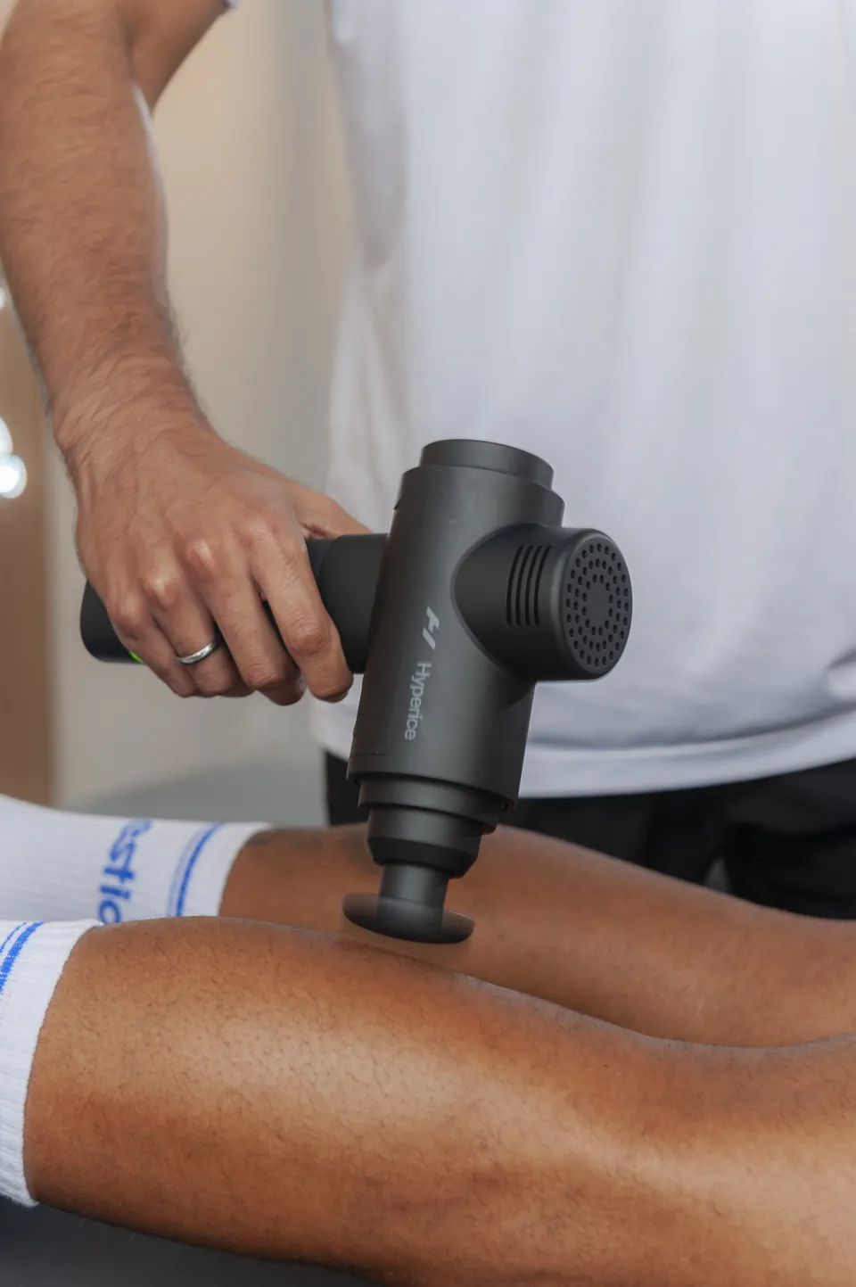 Profissional usando massageador na panturrilha do cliente